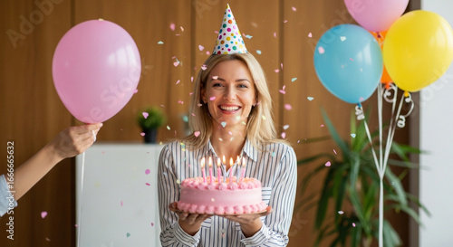 A joyful woman in a party hat celebrates her office birthday with a pink cake and balloons a perfect scene of workplace camaraderie and happy moments with colleagues