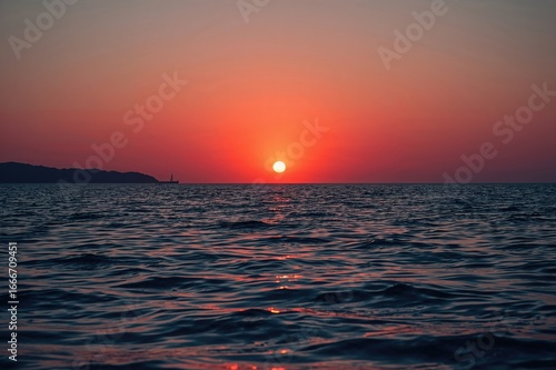 A fiery orange sun ascends ...