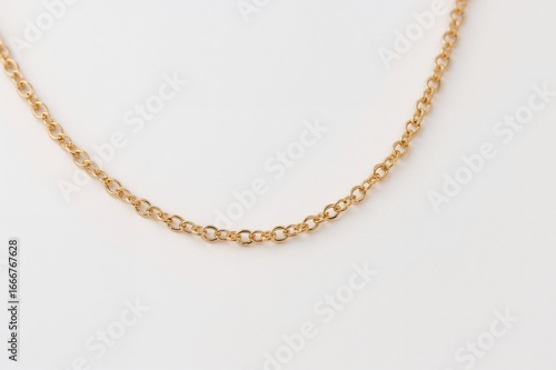 Detailed view of a golden chain necklace set against a white backdrop, showcasing design, elegance, and luxury in metal fashion