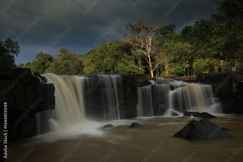 Fototapeta premium Tat Ton is a beautiful waterfall with water flowing all year round, On top of it, the water cascades down wide rock plateaus, with big trees lining up on both side of the stream Chaiyaphum ,THAILAND