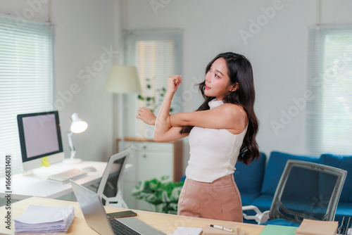 Obraz na plátně Businesswoman stretching arms while working on computer at office desk, taking a