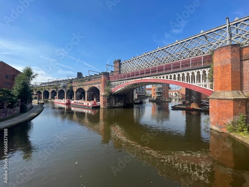 Historic railway bridge over canal with boats in Manchester
