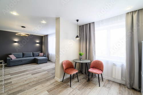 Cozy apartment interior: sofa, chairs, table, curtains, and wood-look flooring in a modern design