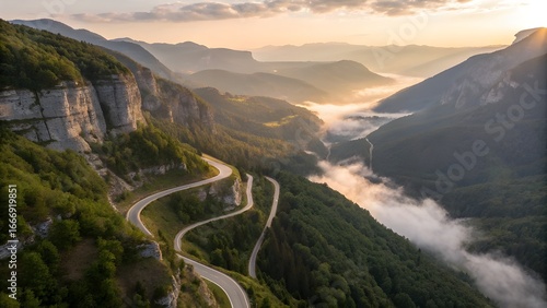 Aerial View of Winding Mountain Road at Sunrise with Misty Valleys