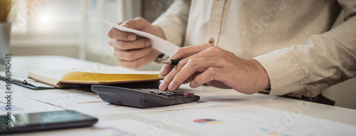 Photos Deduction planning, debt asian accountant hand using calculator to calculating money balance from bill and income, cost budget expenses for pay money form personal individual on table at home