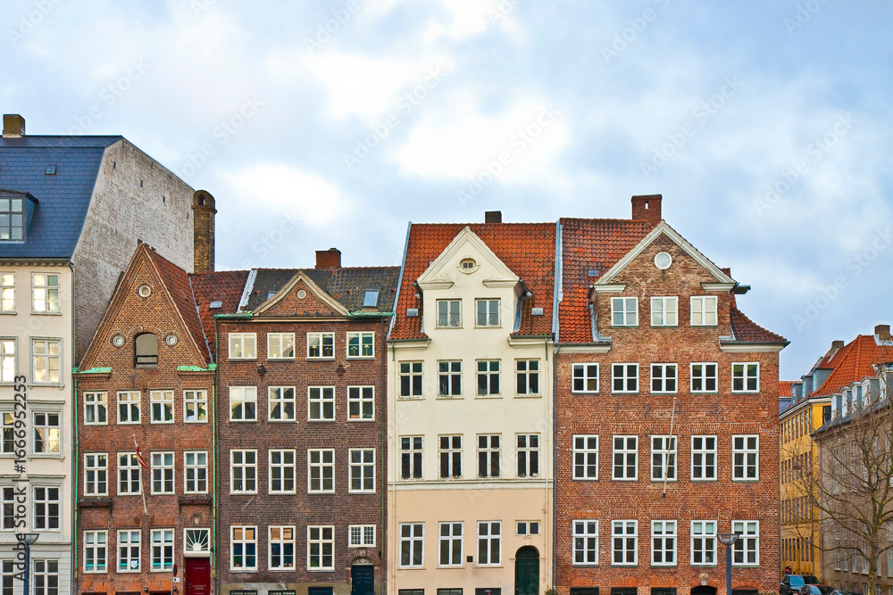 Fototapeta premium COPENHAGEN - Scenic row of traditional European buildings in central Copenhagen, Denmark, featuring classic architecture, red rooftops, and charming facades
