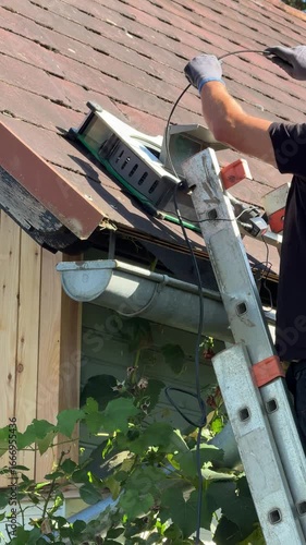 specialist inspecting clogged roof gutter with drill and camera