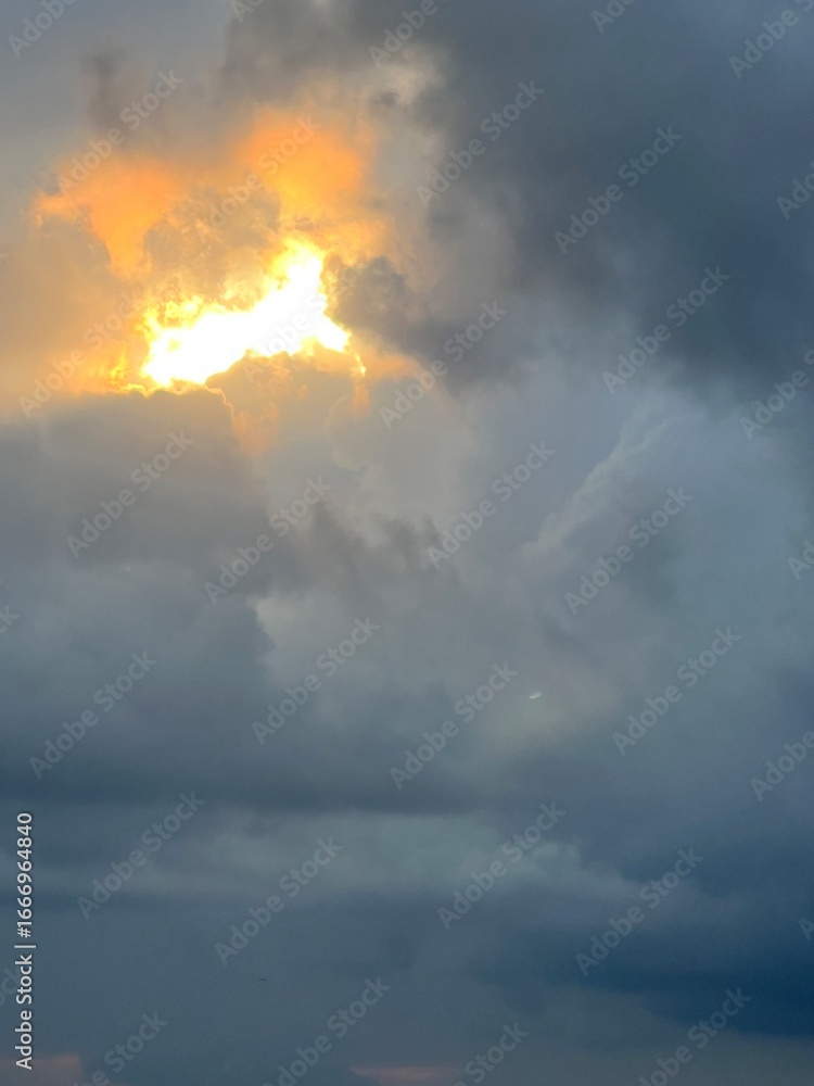 Fototapeta premium Dramatic cloudy sky with glowing sunlight breaking through dark storm clouds creating contrast