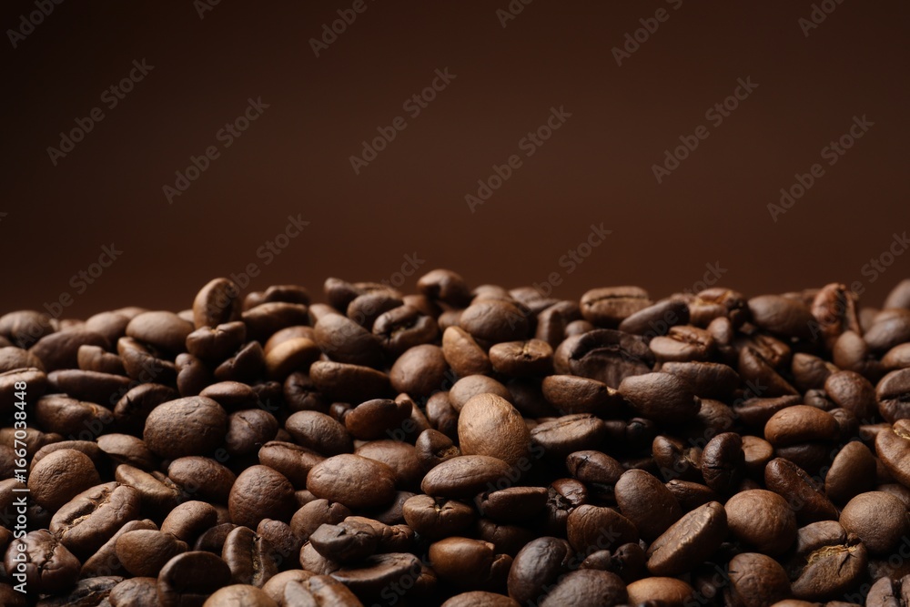 Fototapeta premium Pile of roasted coffee beans on brown background, closeup