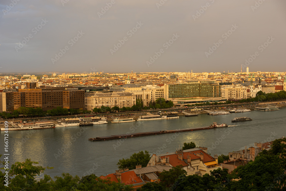 Fototapeta premium the Danube River in Budapest with rainbow at sunset, boats and a barge