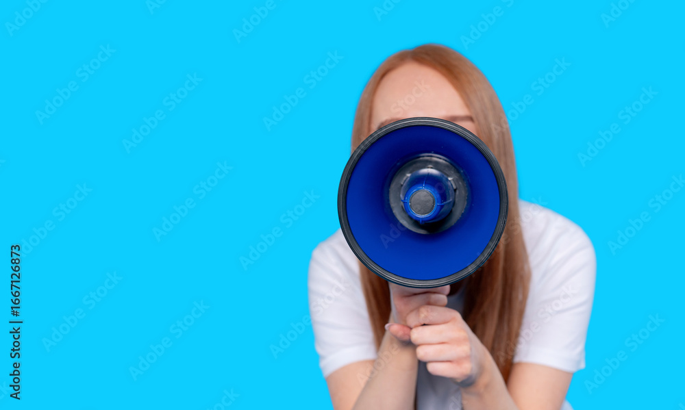 Fototapeta premium Woman holding blue megaphone against solid blue background calling for attention in a public speaking event at a community gathering in the afternoon