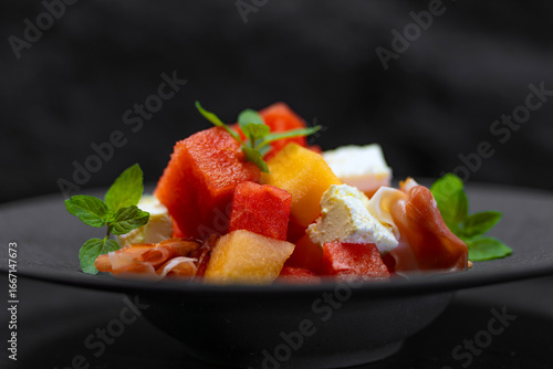 Summer salad with watermelon, melon, cheese, prosciutto, orange zest, and Dijon mustard. Homemade food in summer