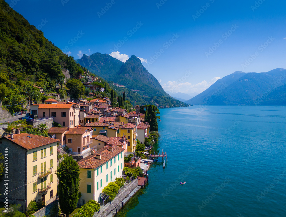 Fototapeta premium Lake Lugano, Valsolda, Italy. View of the lake, mountains and scenic village. A small Italian town by the lake in Albogasio Oria. Aerial drone view