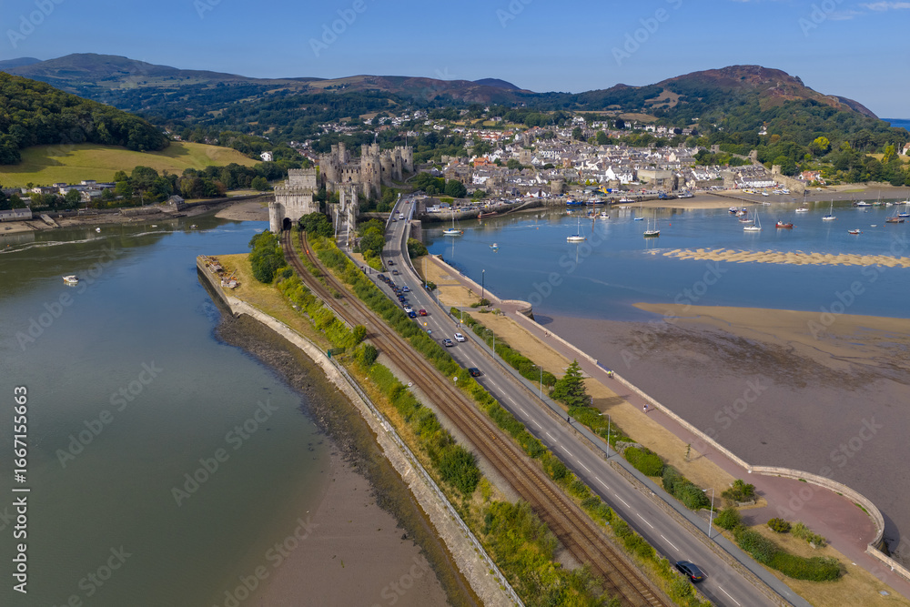 custom made wallpaper toronto digitalAerial view of Conwy Castle, railway line, and road bridge crossing the estuary with the town and mountains in the background on a sunny summer day.