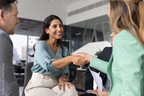 Behang Smiling Brazilian female professional seals successful business interaction with confident handshake during formal meeting with woman colleague or business partner