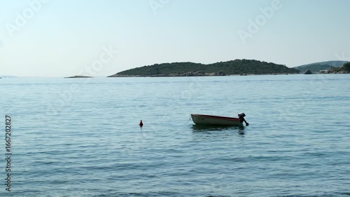 A small boat is floating in the ocean with a buoy attached to it