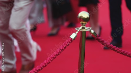 Red carpet with ropes and golden barriers on a luxury party entrance, cinema premiere film festival event award gala ceremony, wealthy rich guests arriving, outdoor decoration elements, summer day