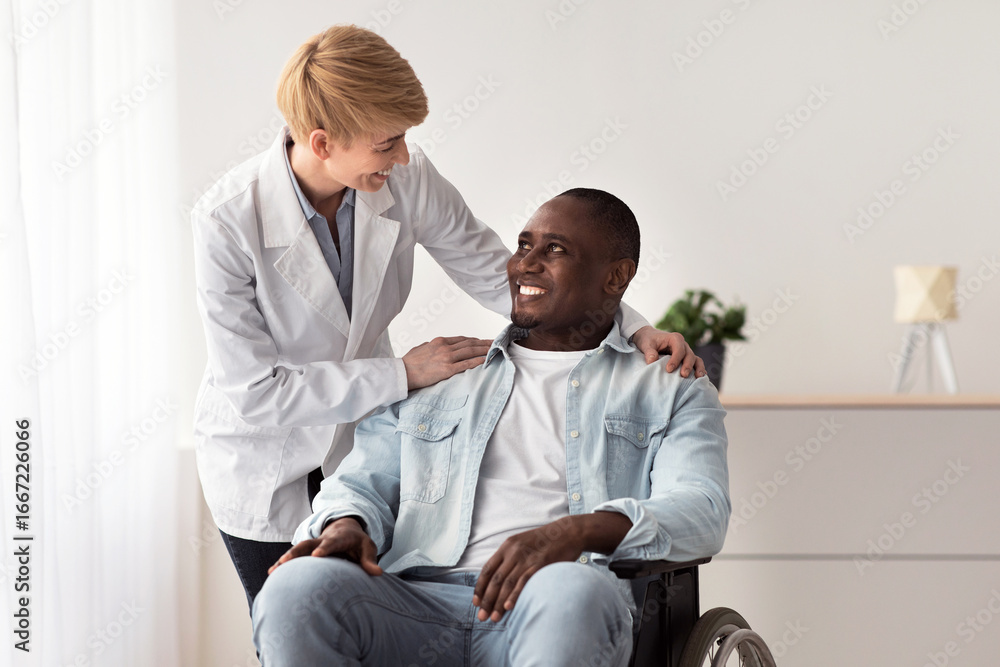 Obraz premium Recovery of disabled after injury and incident, medical support and professional work of physiotherapist. Happy mature lady doctor helping to smiling adult african american guy in wheelchair in clinic