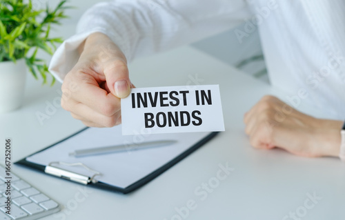A person is holding a piece of paper that says Invest in Bonds