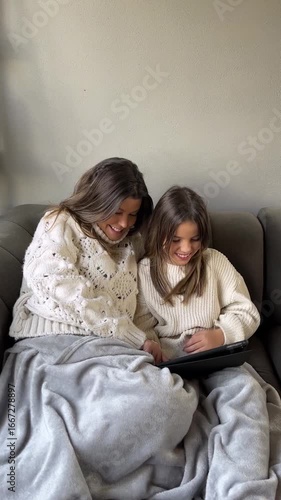 Mother and daughter sharing a cozy moment with tablet on sofa