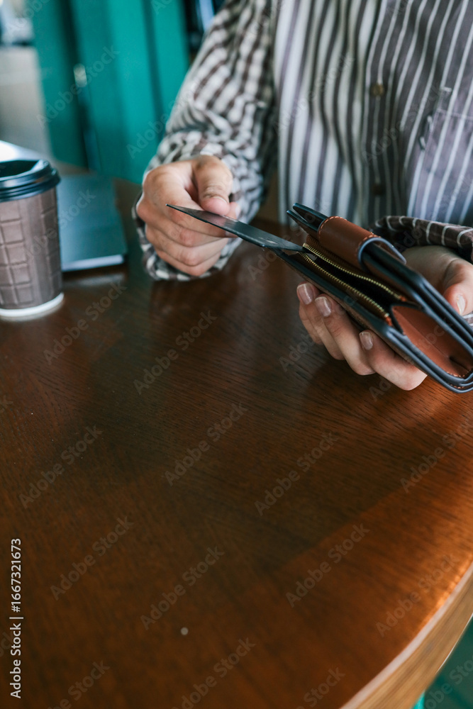 Φωτογραφία Close-up of woman holding wallet with bank card at cafe table, laptop, smartphon