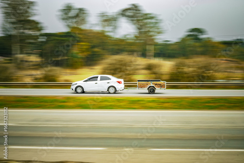 Momentum & Craft: White Sedan Towing Wooden Trailer