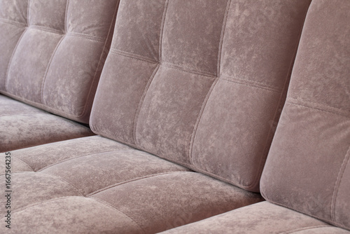 Close-up of pink quilted velour sofa. Soft furniture for relaxation covered with dusty rose plush material.