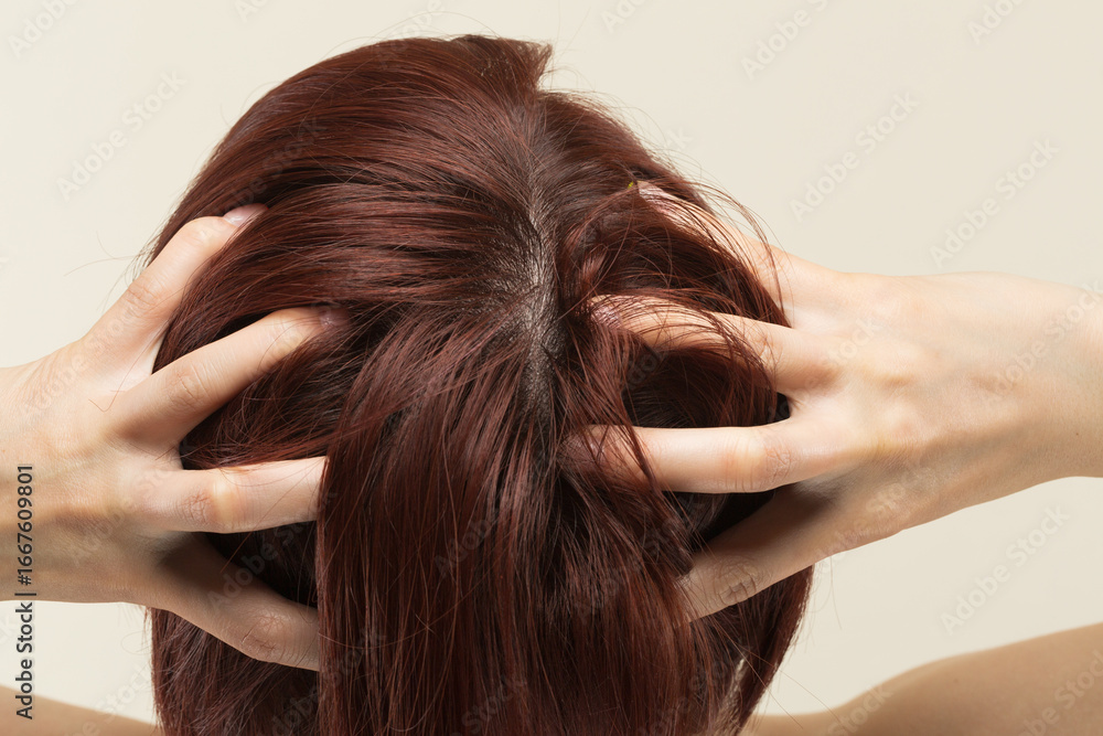 Naklejka premium 若いアジア人の女性は頭皮をマッサージしています。