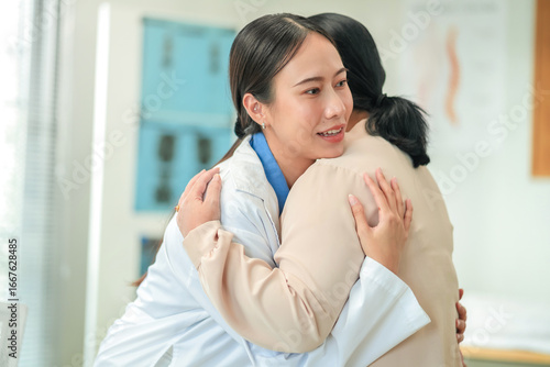 Obraz na plátně Happy Asian female doctor demonstrates compassionate care, holding hands with senior patient