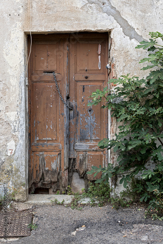 old, rotten wooden door with partially rotten boards and steel chain