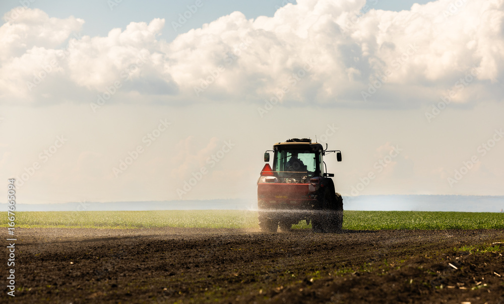 Fototapeta premium Tractor spreading artificial fertilizers in field