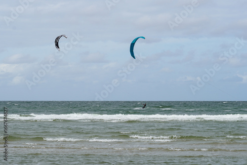 Kitesurfers Riding Waves on the Open Sea