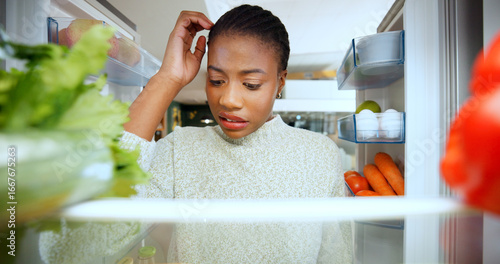 Woman, thinking and confused at fridge in home, choice and scratch head for food in morning. African person, decision and check shelf for healthy diet, ingredients and POV in kitchen at apartment