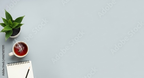 Serene Workspace Flat Lay with Steaming Tea, Plant, and Notebook on a Grey Banner