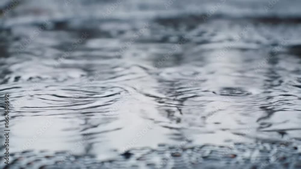 Close up of rain falling on water forming ripples and circles Close up of rain falling on water forming ripples and circles