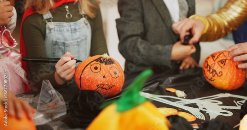 Fotografie Hands, halloween and group with pumpkin, decoration and creativity with drawing, costume and party