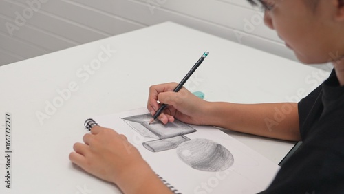 Принти на полотні Student practicing pencil drawing of 3D geometric shapes in sketchbook