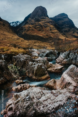 фотографія River Coe flows through Glen Coe with The Three Sisters mountains in early sprin