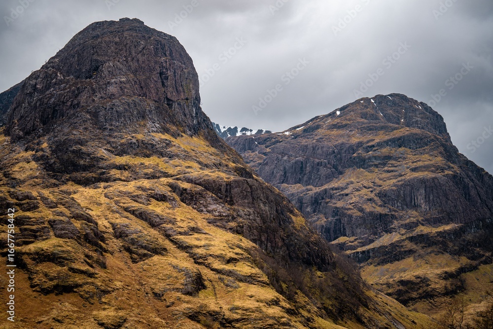 Obraz premium Majestic view of the Three Sisters mountains in Glencoe, Scotland under a dramatic cloudy sky