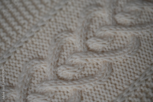 white texture of knitted wool fabric as a background, ivory smooth symmetrical braided cable knit pattern of hand-knitted needlework