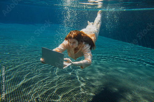 Quadro em tela Businesswoman working on laptop underwater in swimming pool