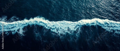 Fototapeta Naklejka Na Ścianę i Meble -  Aerial perspective of powerful ocean waves with white foam cresting against deep blue water, showcasing the raw beauty of nature