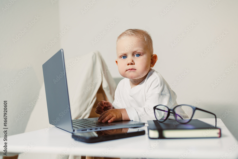 A curious baby is fully engaged with a laptop placed on a clean, white table, which is surrounded by a collection of books and glasses, highlighting the beauty of learning and exploration A curious baby is fully engaged with a laptop placed on a clean, white table, which is surrounded by a collection of books and glasses, highlighting the beauty of learning and exploration