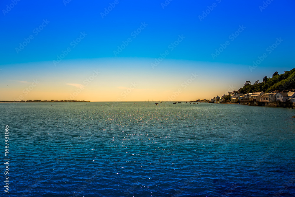 Obraz premium Tranquil Coastal Sunset Over Aberdovey, Wales, with Sparkling Blue Waters, Seaside Cottages, and Fishing Boats on the Horizon
