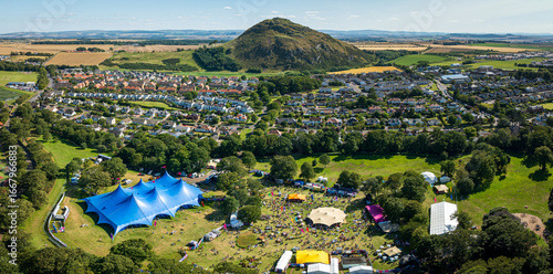 Aerial view of a vibrant festival with colorful tents and bustling crowds set against the backdrop of a lush green landscape, Haddington, Scotland, United Kingdom.