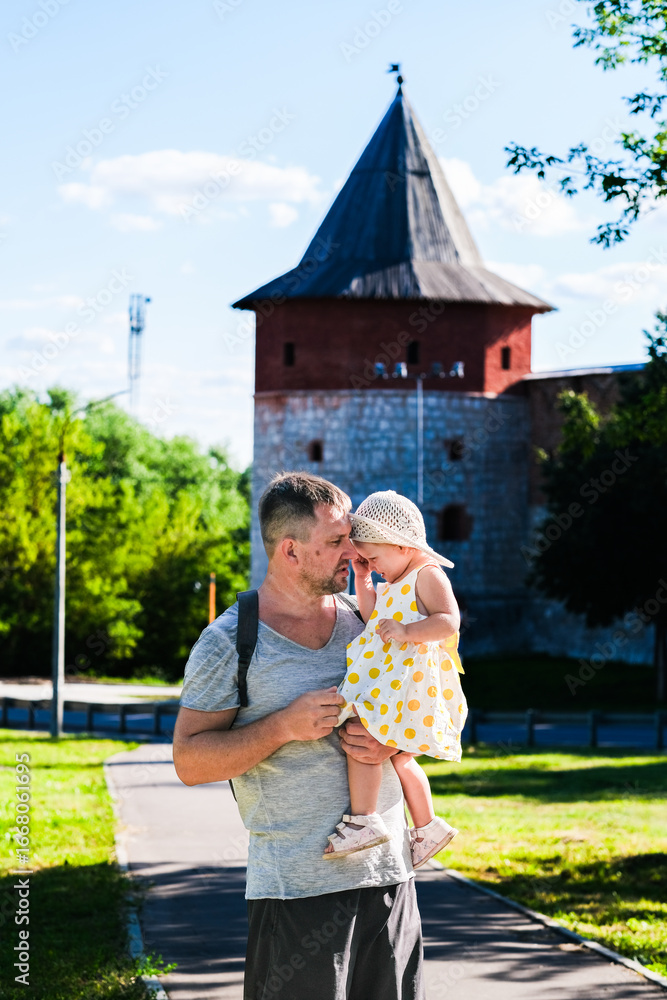 Fototapeta premium Zaraysk, Russia, 06.07.2024. A man is holding a young girl in a yellow dress