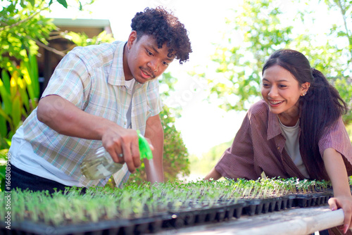 Male and female students checking vegetable growth and taking notes, symbolizing education and learning.