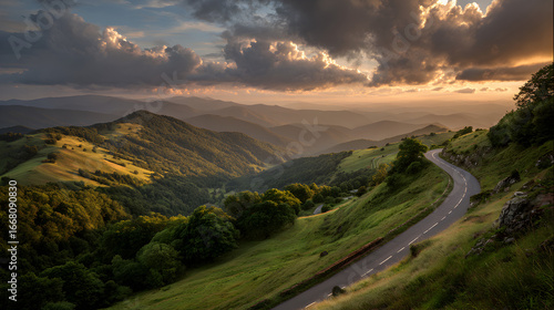Winding mountain road through lush green hills under dramatic golden sunset sky scenic travel background