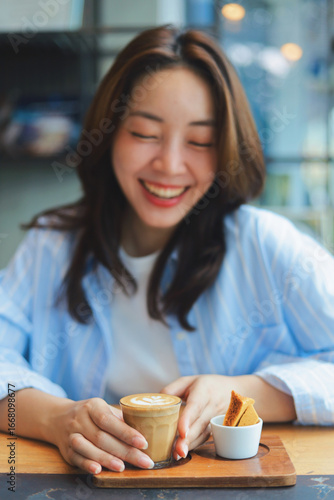 Close up Asian woman hands holding a cup of hot coffee at modern cafe, representing freelance lifestyle, digital nomad, and online business success