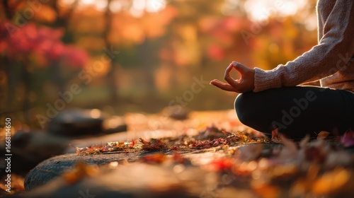 Close-up of a person meditating in a tranquil autumn forest. Woman practicing yoga and mindfulness in nature with golden fall leaves, promoting wellness, calm, and stress relief